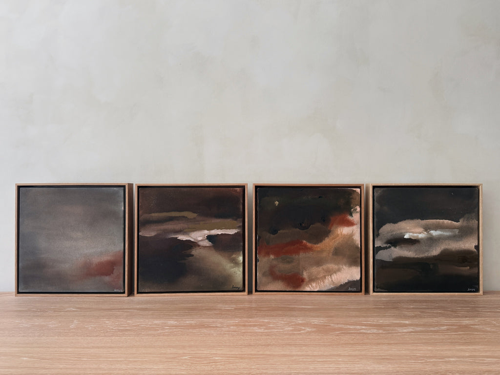 Four framed abstract artworks on a wooden surface with a neutral background