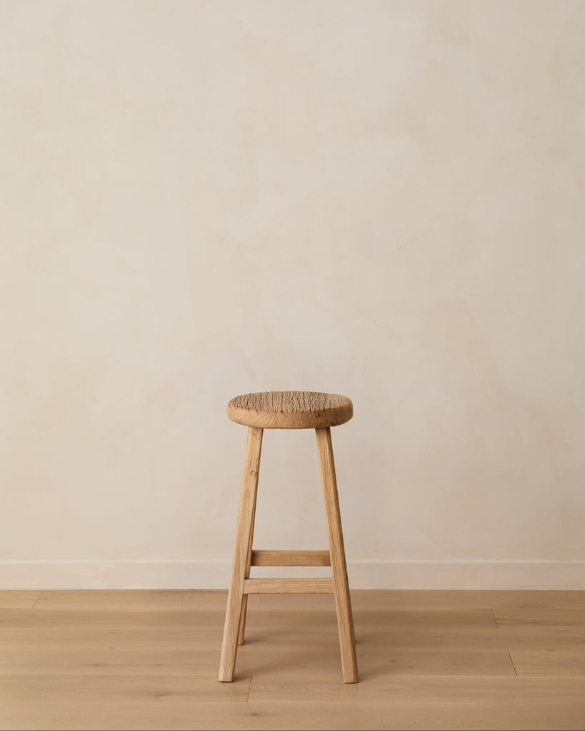Vintage Reclaimed Elmwood Counter Stool against beige lime washed wall and oak floor.