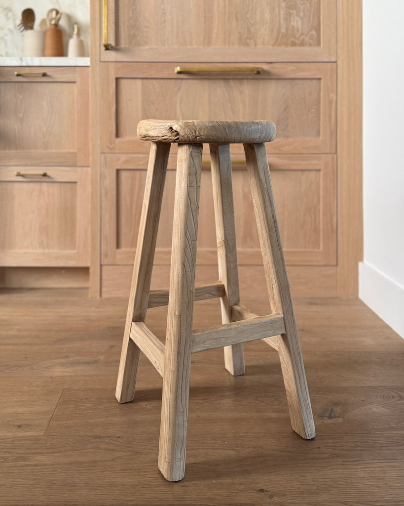 Vintage Elmwood Counter stool in a kitchen setting with oak cabinets and floor.