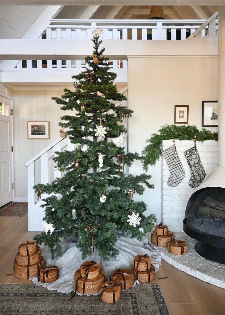 Decorated Christmas tree with tenganan baskets and stockings in a home setting.