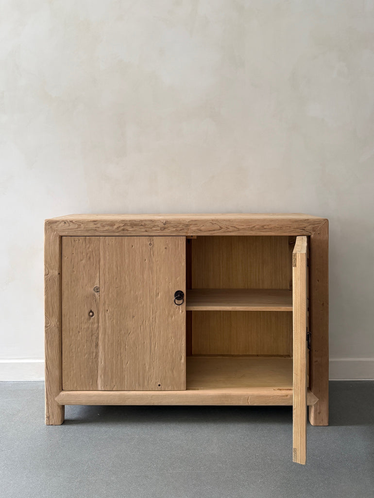 Vintage Reclaimed Elmwood cabinet with one door open styled against a beige limewashed wall. Saffron + Poe