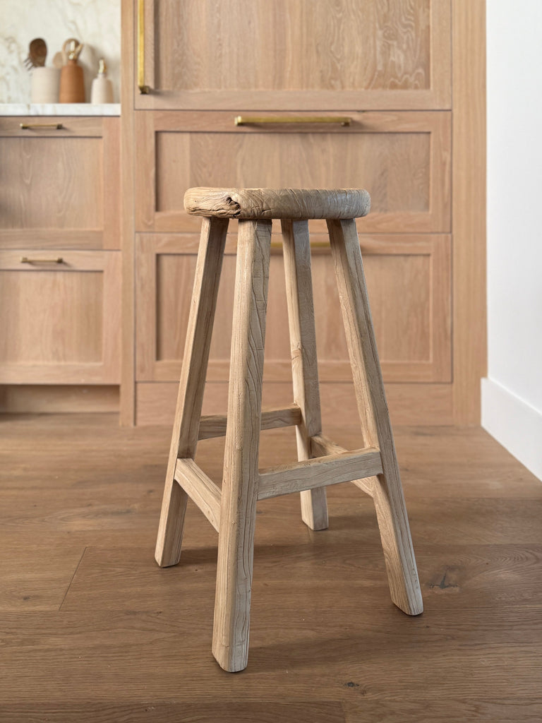 Vintage Elmwood Counter stool in a kitchen setting with wooden cabinets. Saffron + Poe