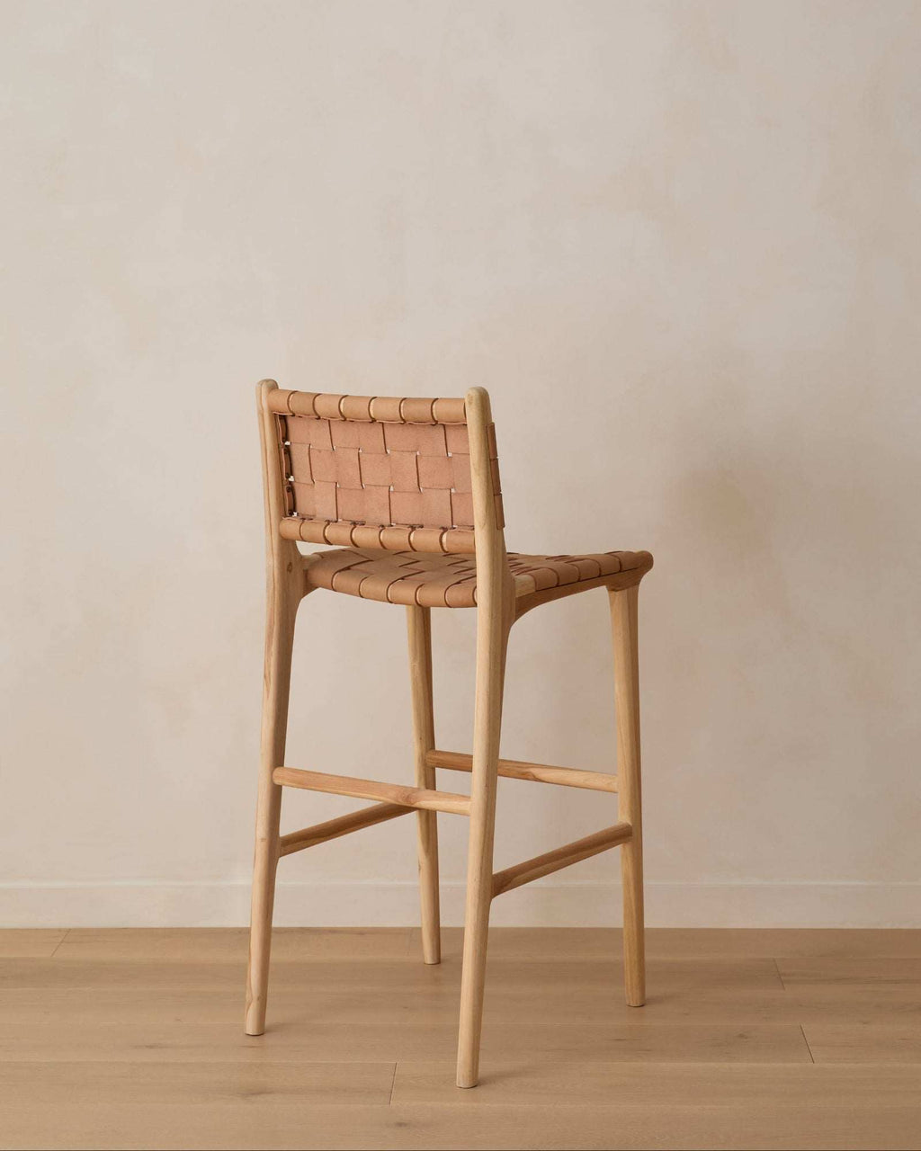 Beige woven leather bar stool with handwoven straps and teak wood frame in natural matte finish