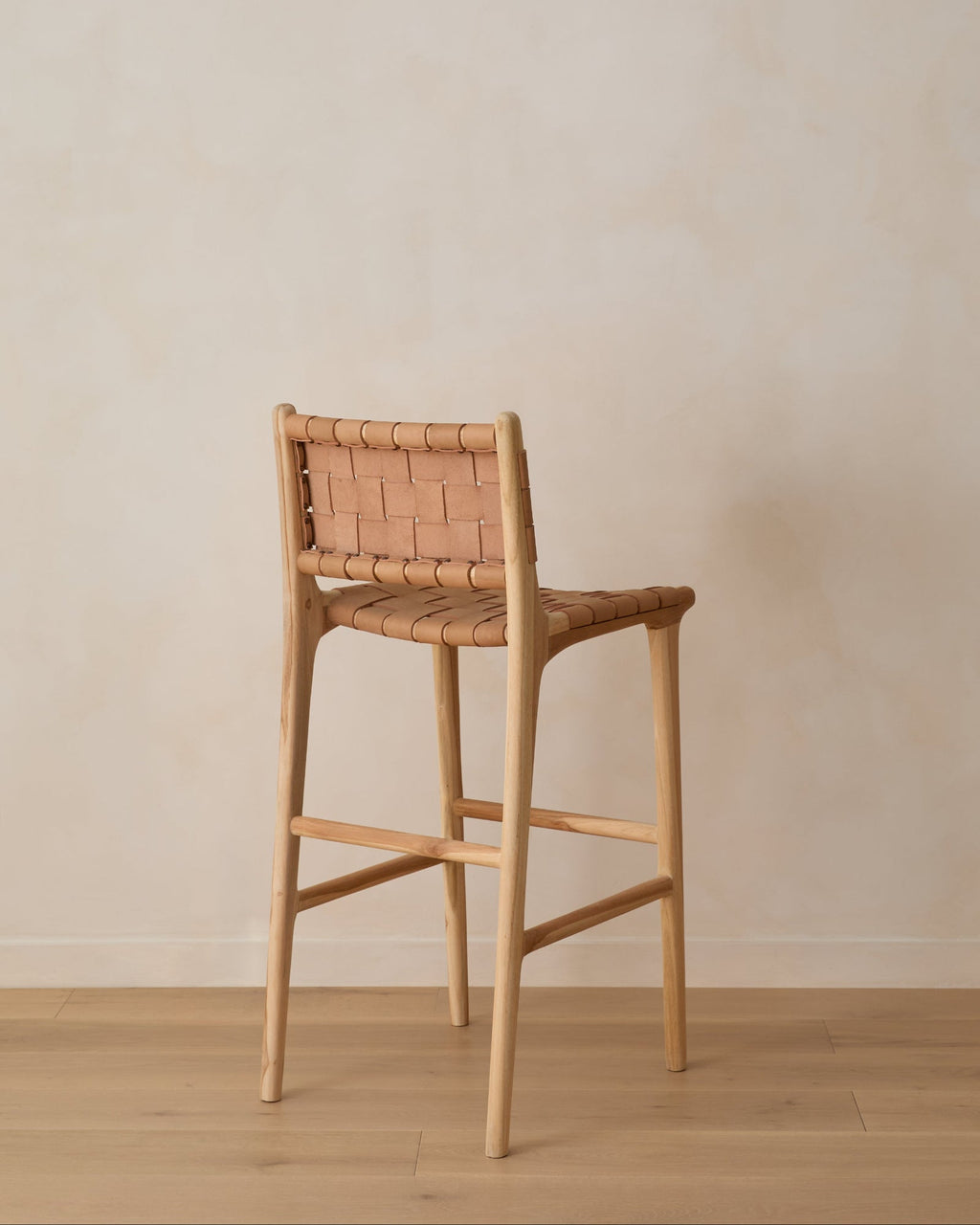 Beige woven leather bar stool with handwoven leather straps and teak wood frame in natural matte finish