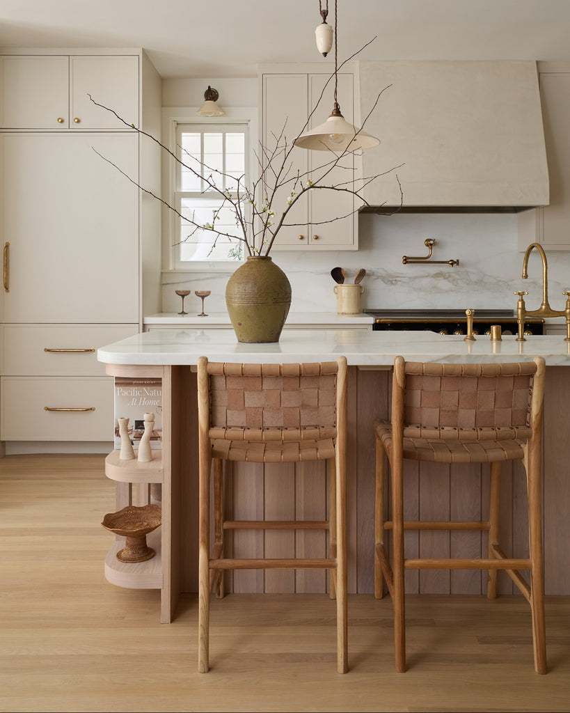 Modern kitchen with wooden cabinets, beige woven leather counter stools, and neutral accents