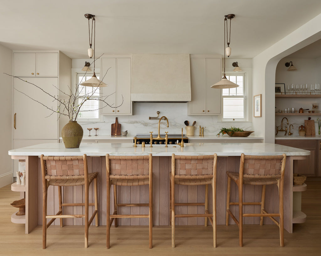 Modern kitchen with beige woven leather counter stools at large oak and marble island
