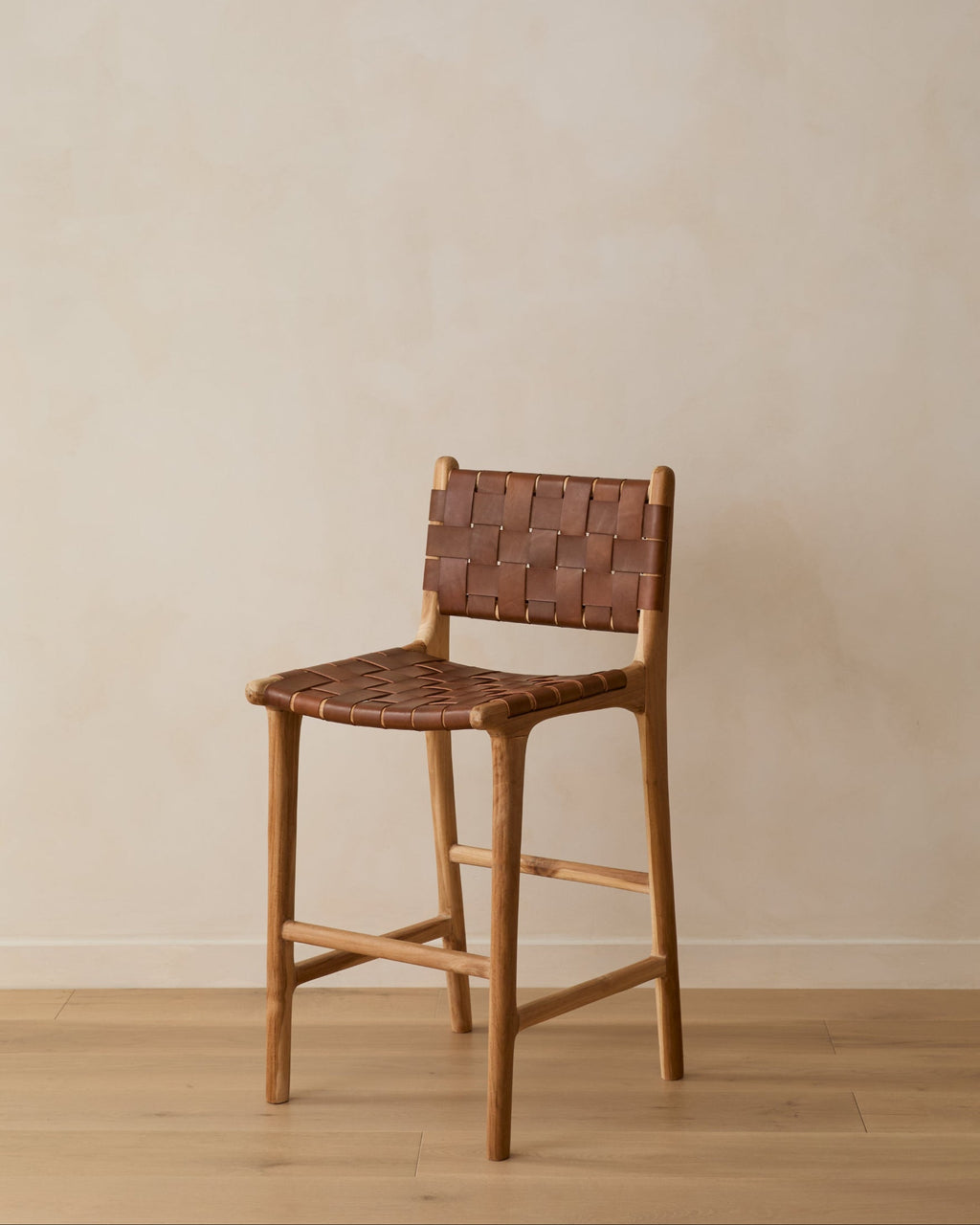 Woven leather counter stool in saddle color with carved teak frame and woven leather straps