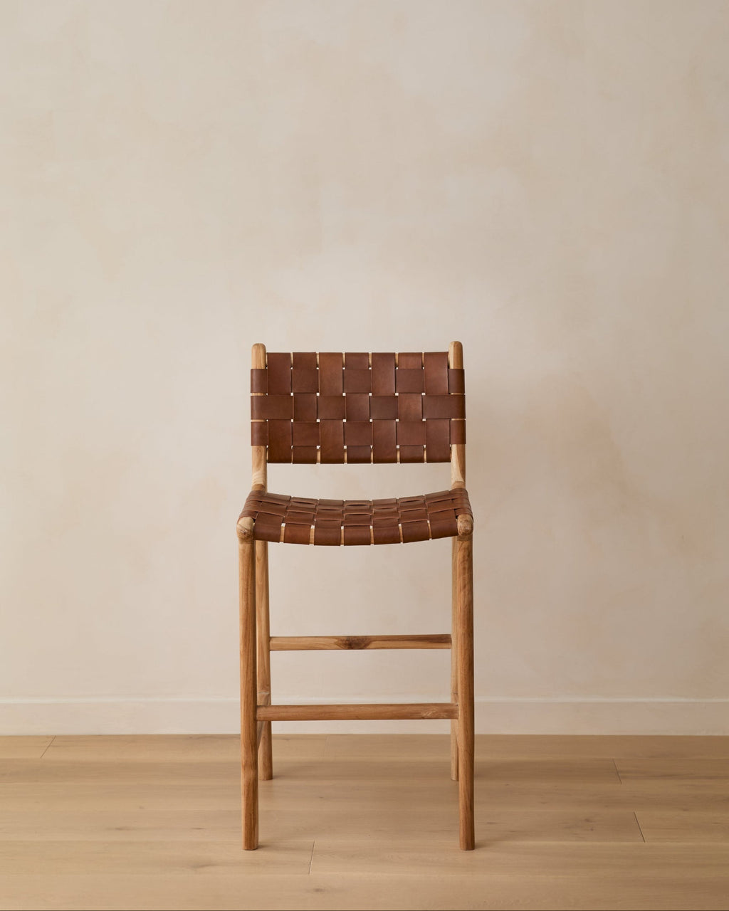 Woven leather counter stool in saddle color with carved teak frame and woven leather straps