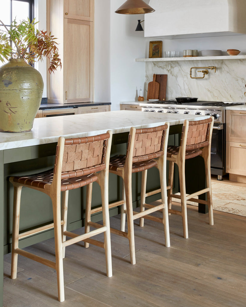 Saddle Woven leather counter stool styled at green island in old-world European but modern kitchen. 