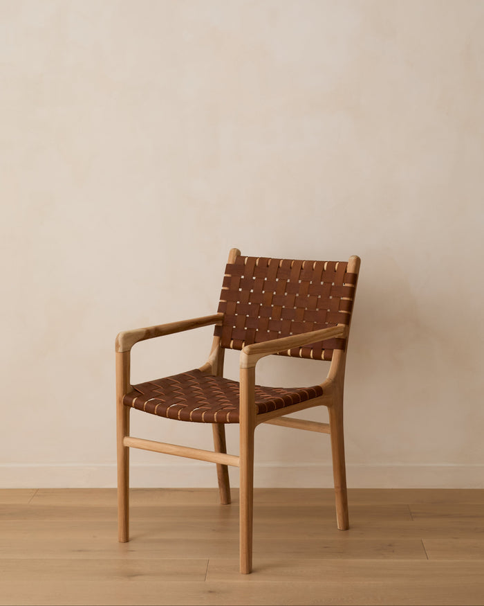 Front Angle view of our woven leather strap dining arm chair in saddle against lime washed wall and oak floors. 