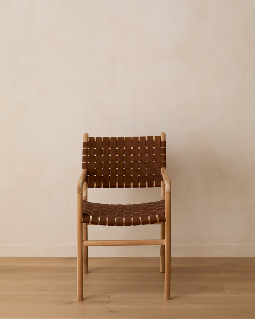 Front view of our woven leather strap dining arm chair in saddle against lime washed wall and oak floors. 