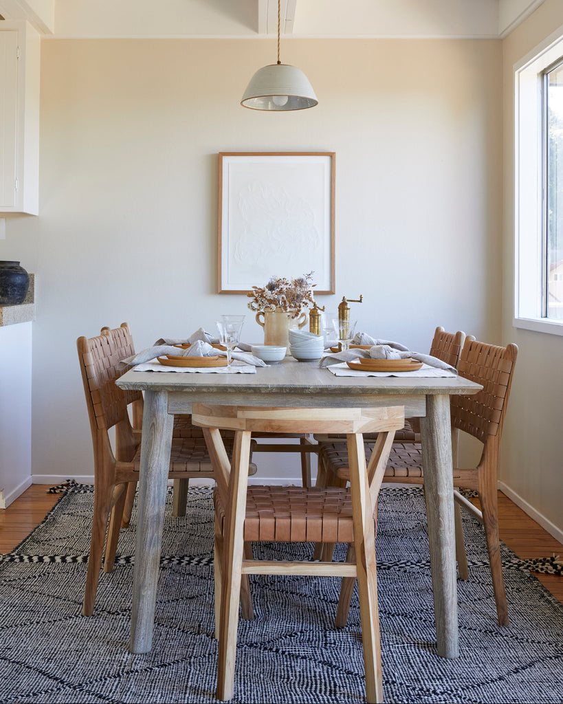 Woven Leather Strap Dining Chair in beige leather styled in a dining room with ceramic pendant and Moroccan Kilim rug