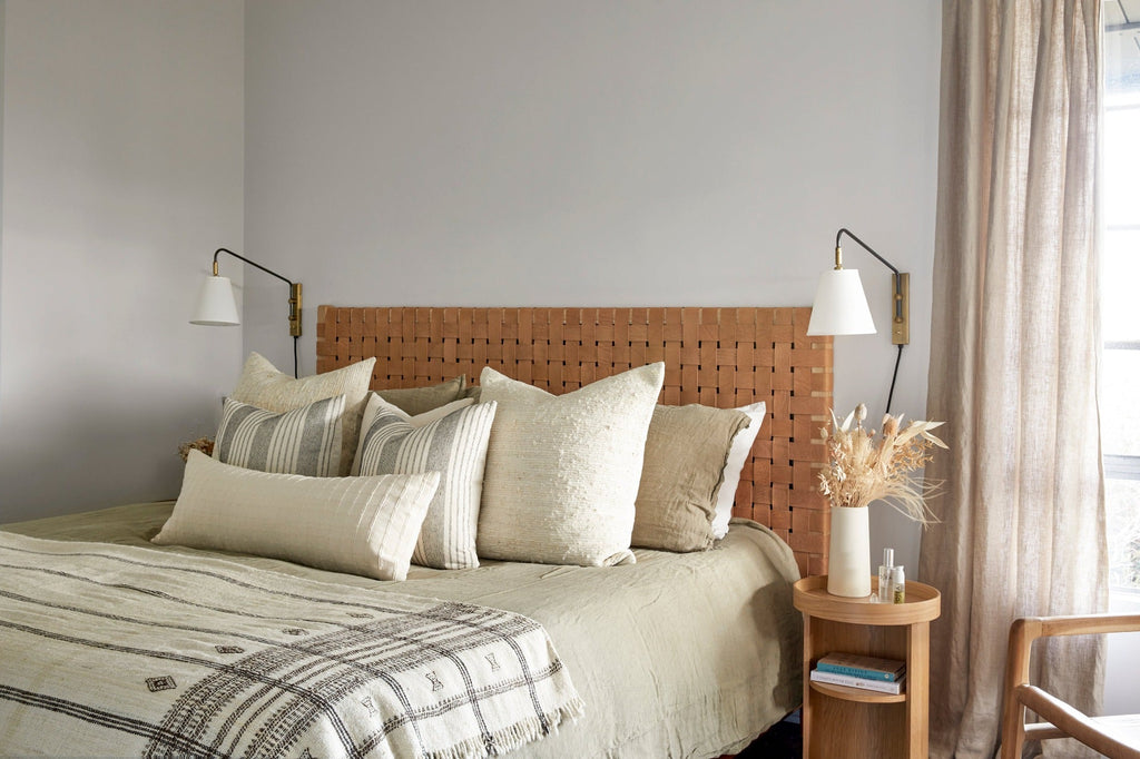 Woven Leather Headboard in a bedroom setting with Ivory Handwoven Columbian Pillows, Ivory Embroidered Lumber Pillow,  Ivory Embroidered Pillow No. 3, Bhujodi Throw, and Natural Linen Bedding. - Saffron + Poe 