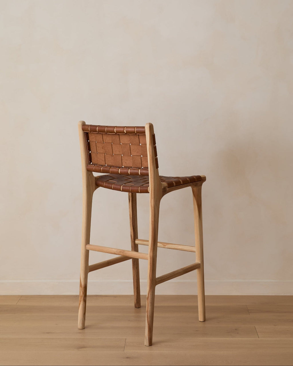 Woven leather bar stool in saddle color with teak frame and woven straps