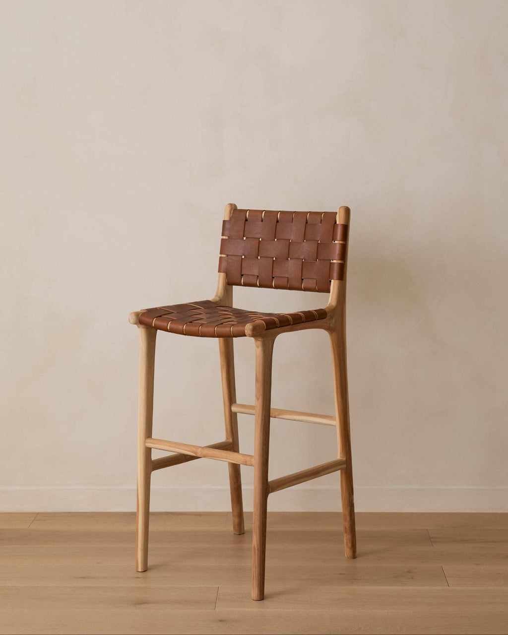 Woven leather bar stool with saddle straps on carved teak frame in natural matte finish