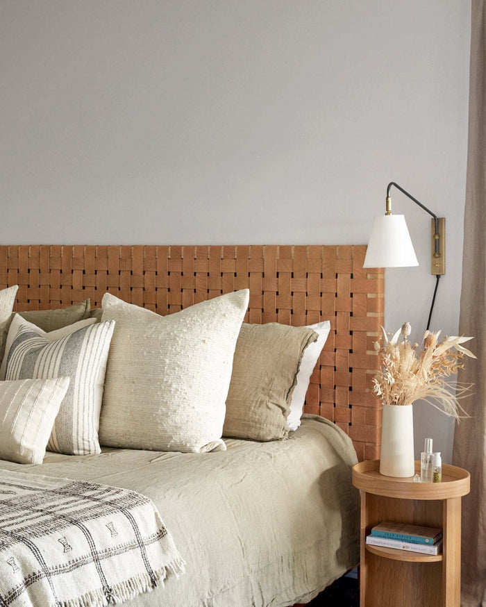 Woven leather strap headboard with teak frame in beige color styled in a bedroom with pillows, handcrafted in Bali