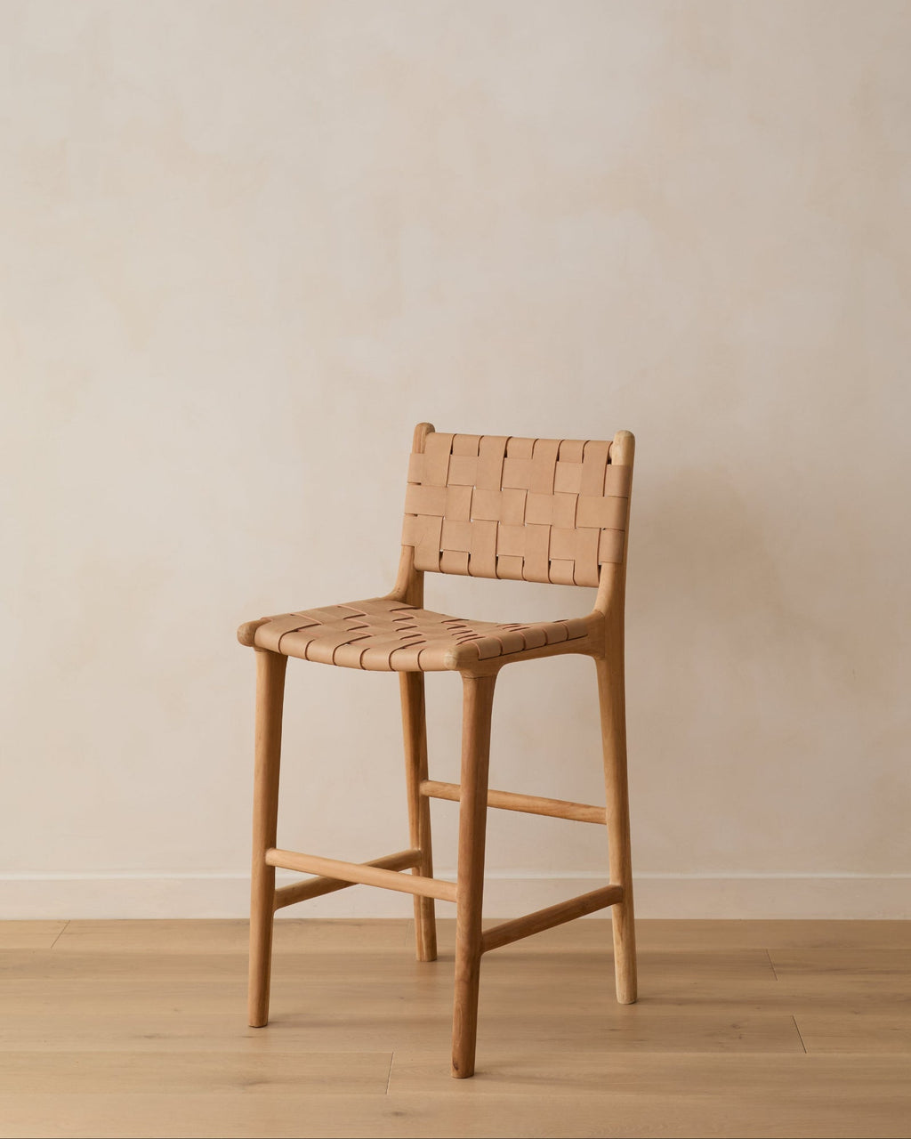 Beige woven leather counter stool with handwoven straps and teak wood frame