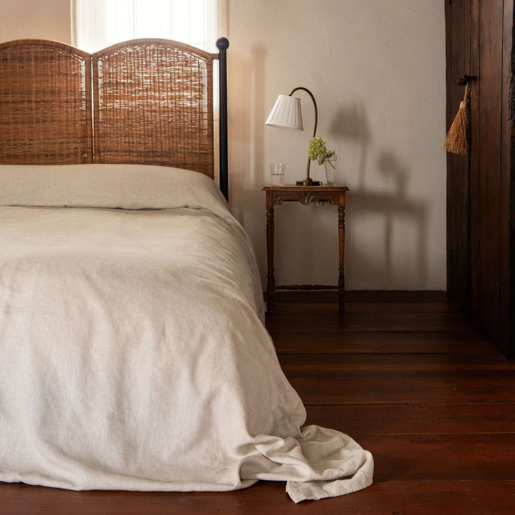 Rattan Lacoste King Bed with woven headboard, black iron frame, and wooden nightstand in a bedroom setting.