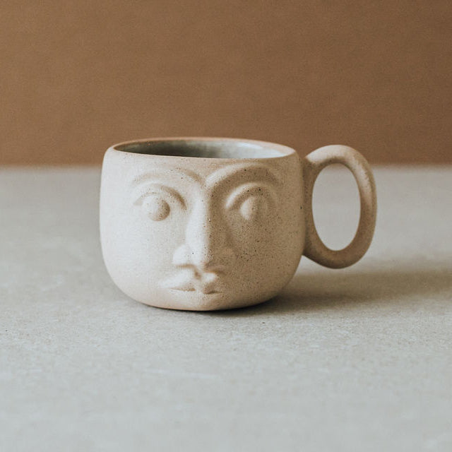Handcrafted ceramic face mug with earth tone textures and glazed interior