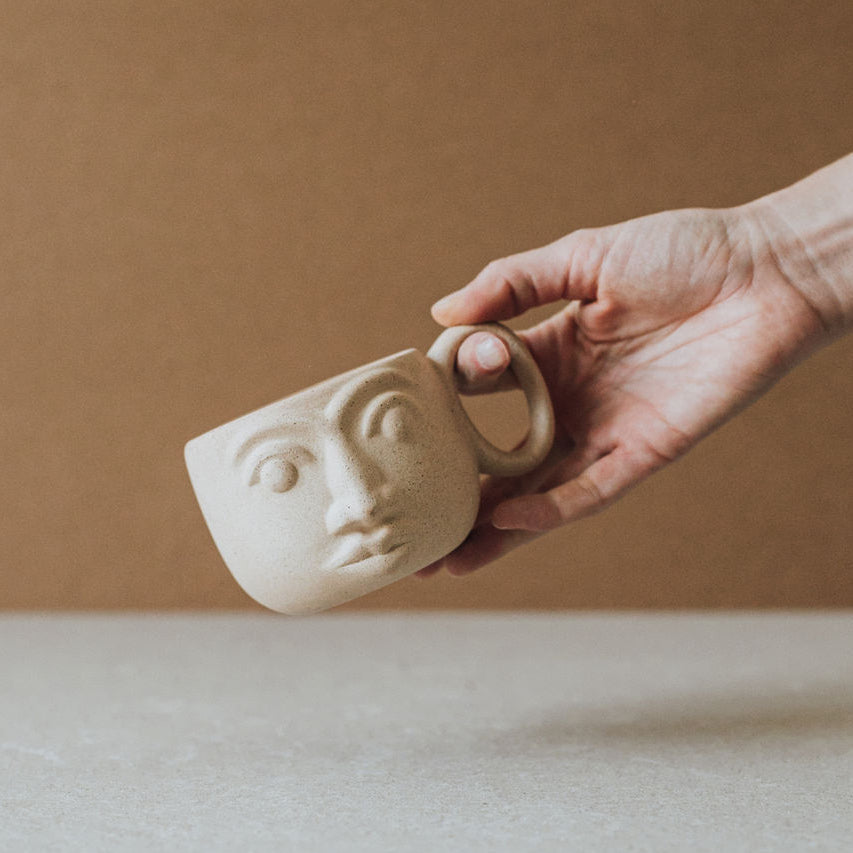 Handcrafted ceramic face mug with earth tone textures and glazed interior