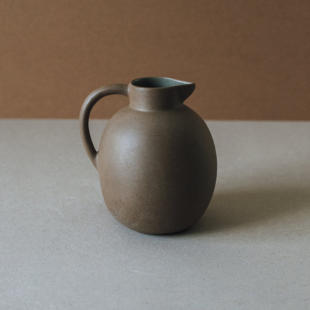 Handcrafted ceramic ball pitcher with natural earth tones and glazed interior