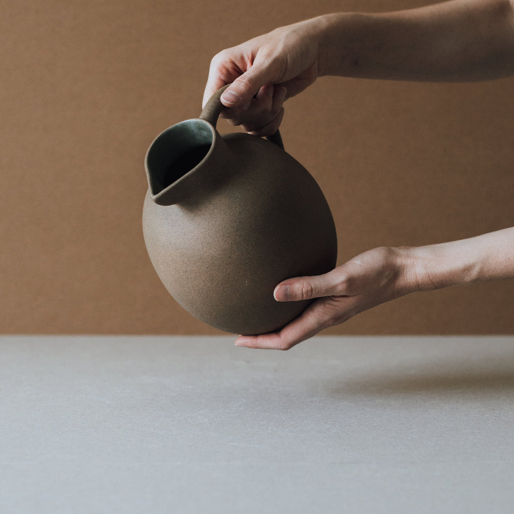 Handcrafted ceramic ball pitcher with earth tone glaze interior and natural clay exterior