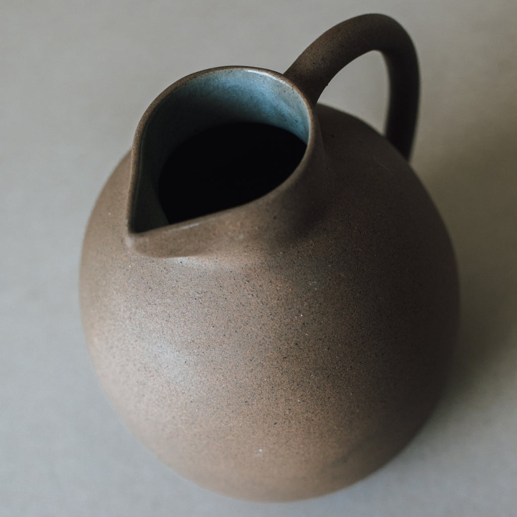 Handcrafted ceramic ball pitcher with natural earth tones and glazed interior, 50 oz capacity