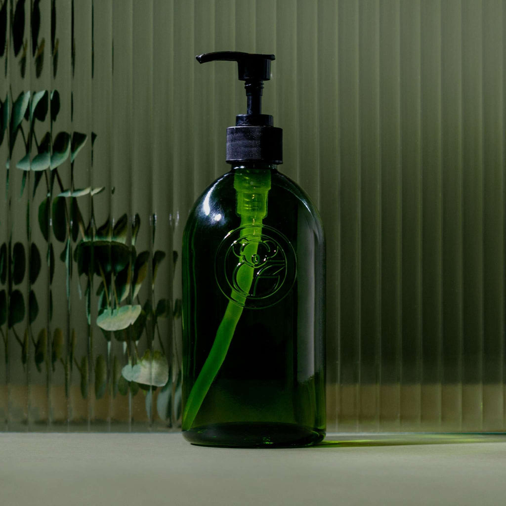 Apothecary Glass Bottle in dark green recycled glass with a black pump dispenser and classic rounded shape