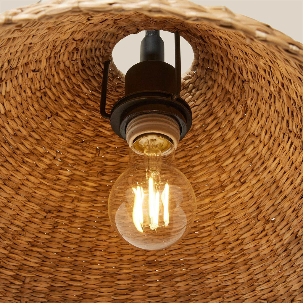 Bainbridge Oversized Swing Arm Sconce with a natural tan seagrass woven shade and dark metal socket, shown with an exposed bulb