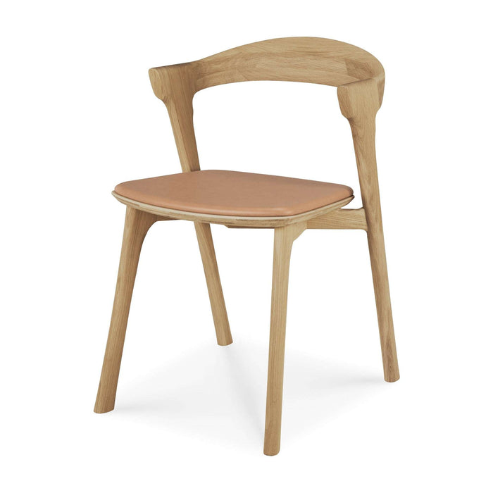 Bok Dining Chair in warm oak with a curved contoured frame and smooth beige leather seat