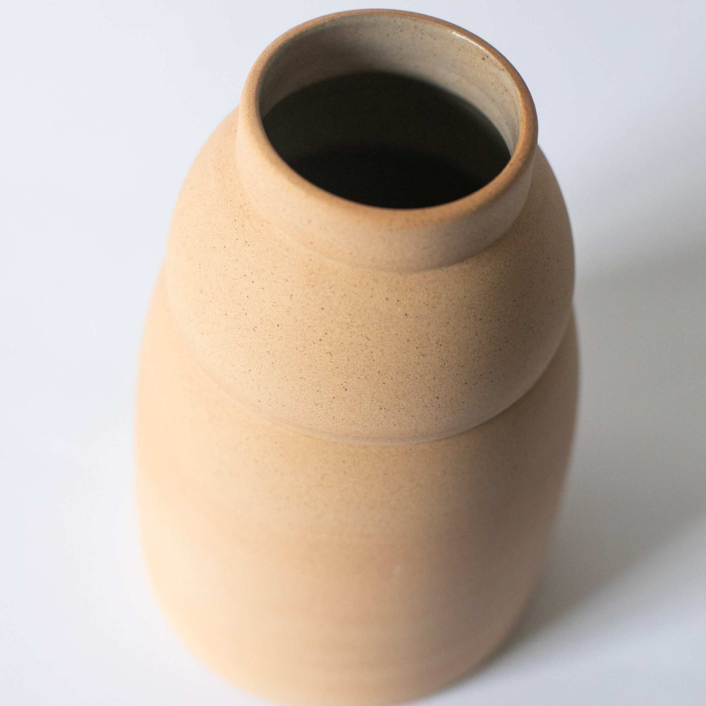 Handmade chubby ceramic vase with unglazed earthy exterior and glazed interior showcasing natural clay tones