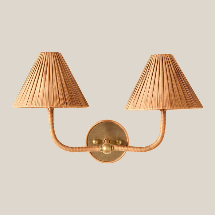 Delphine Double Sconce with two pleated natural rattan shades, a wrapped rattan frame, and warm brass wall plate
