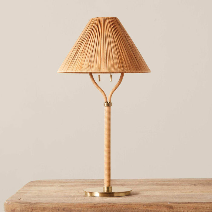 Delphine Table Lamp with a natural woven rattan shade and slender wrapped stem, finished with a round brass base
