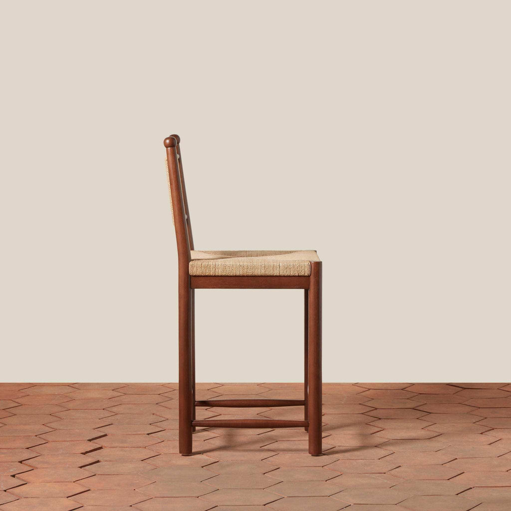 Estela Counter Stool in warm brown wood with a woven rush seat and tall spindle back