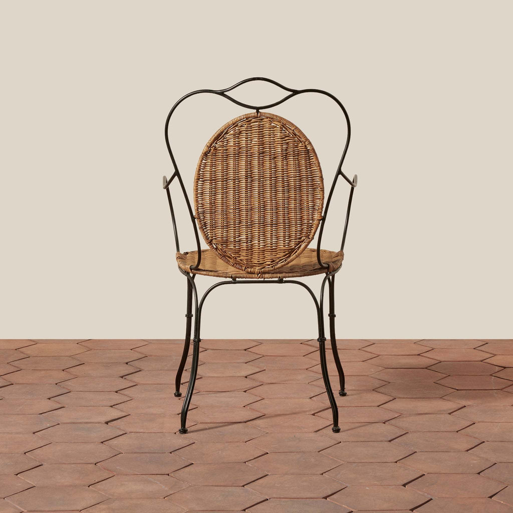 Lacoste Indoor/Outdoor Wicker Arm Chair featuring a round rattan woven backrest and seat with slender black wrought iron frame and curved armrests