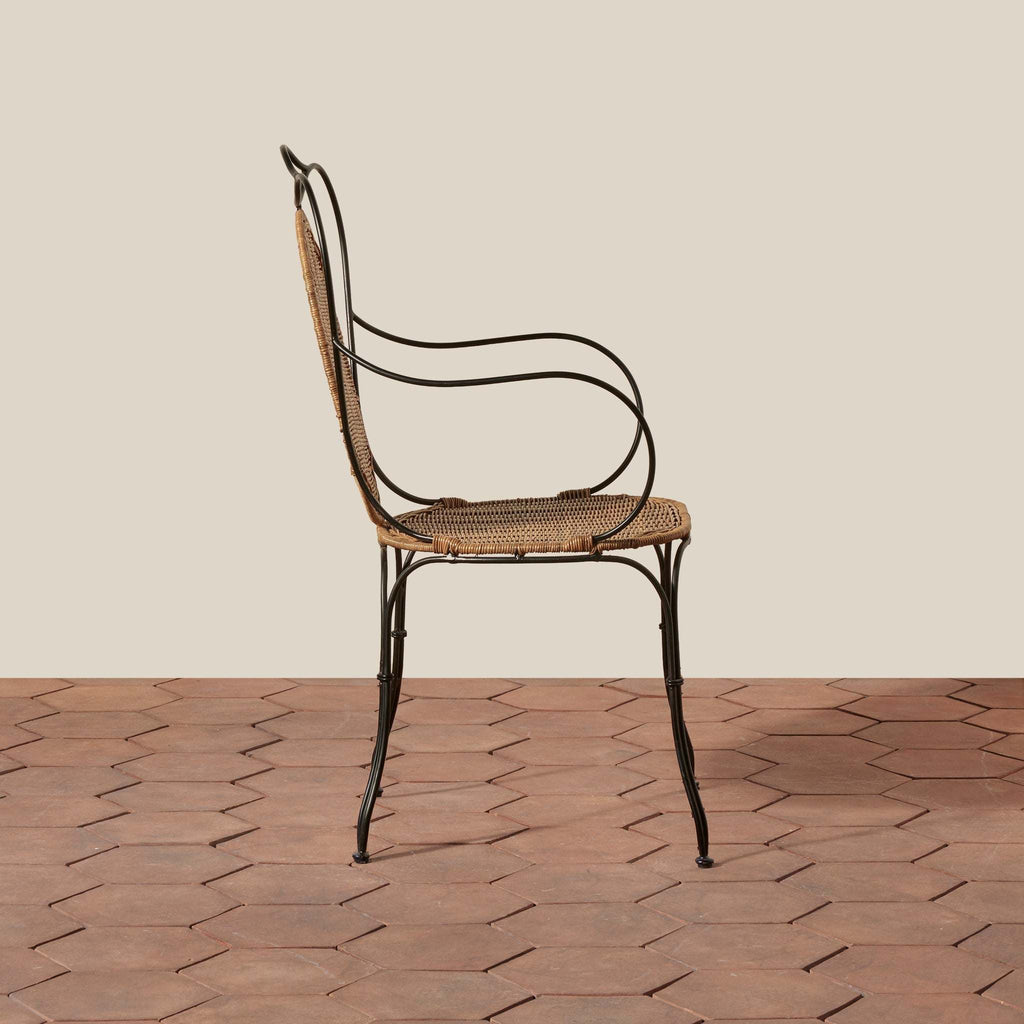 Lacoste Indoor/Outdoor Wicker Arm Chair with brown woven rattan seat and backrest, and black wrought iron curved arms and legs