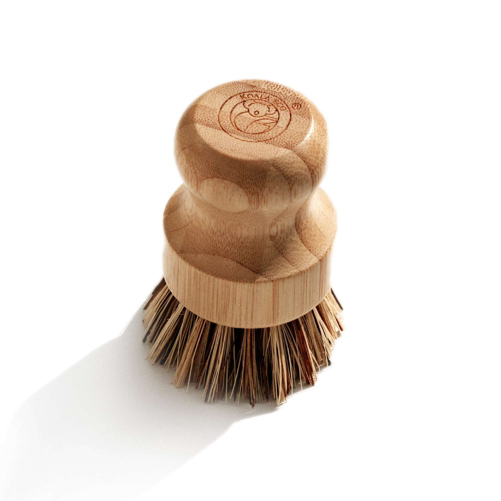 Scrubbing Brush with a rounded natural bamboo handle and dense dark sisal bristles, topped with a stamped logo