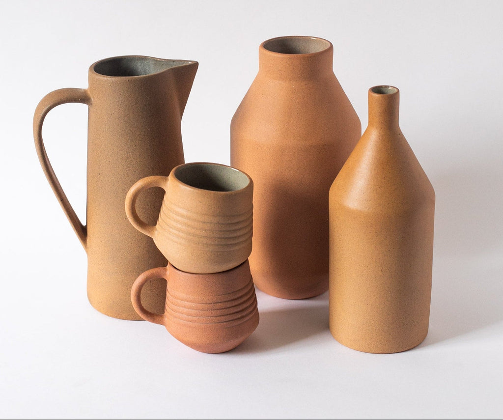 Handcrafted tall ceramic pitcher with natural earth tones and unglazed exterior