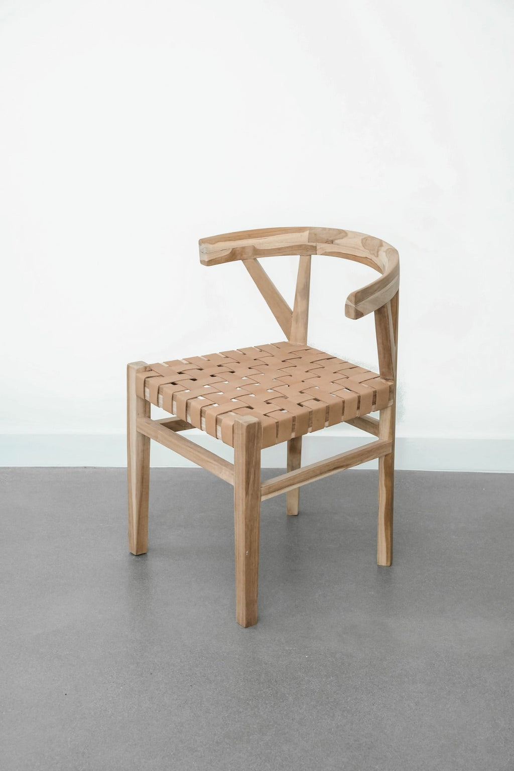 Woven leather Wishbone dining chair with teak frame and beige strap seat on gray floor