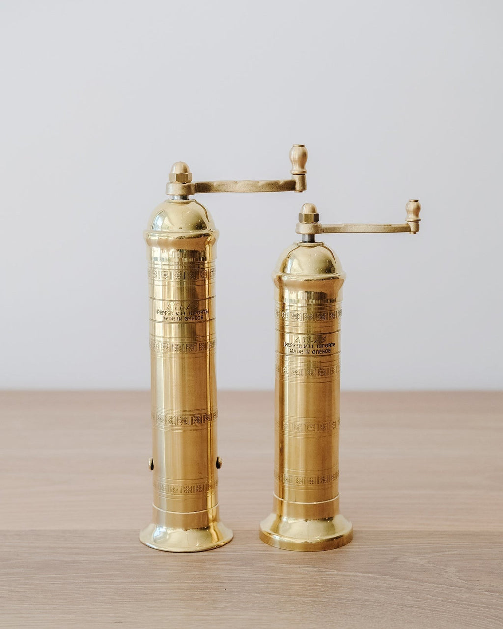 Atlas Brass Salt and Pepper Grinder Set with adjustable grinding feature on wooden surface