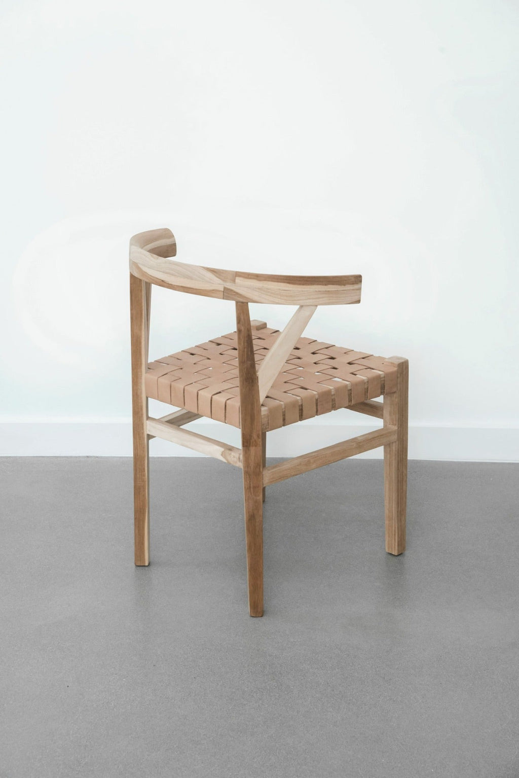 Woven leather Wishbone dining chair with hand-carved teak frame and beige woven seat in modern minimalist setting