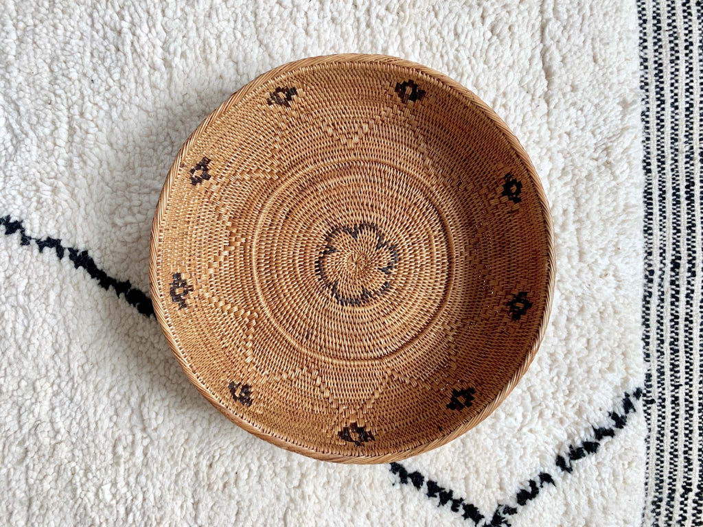 Handwoven Black and Natural Tenganan Basket with intricate patterns on textured white and black rug