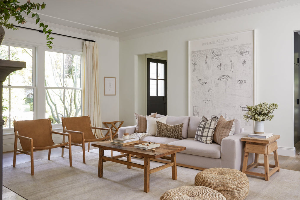 Vintage Wood Coffee Table in a living room setting with Leather Sling Lounge Chair, Natural Poufs, Vintage Side Table, and Ceramic Vase. - Saffron + Poe 