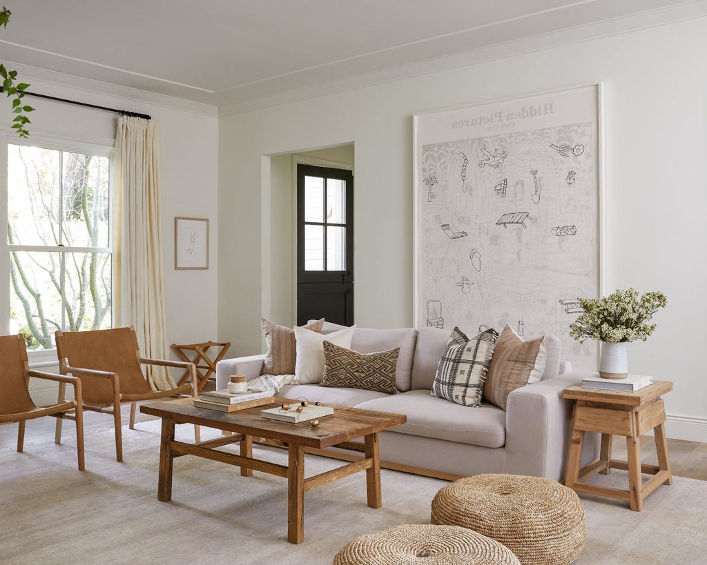 Rustic vintage cedar end table in a bright living room with beige sofa and leather chairs