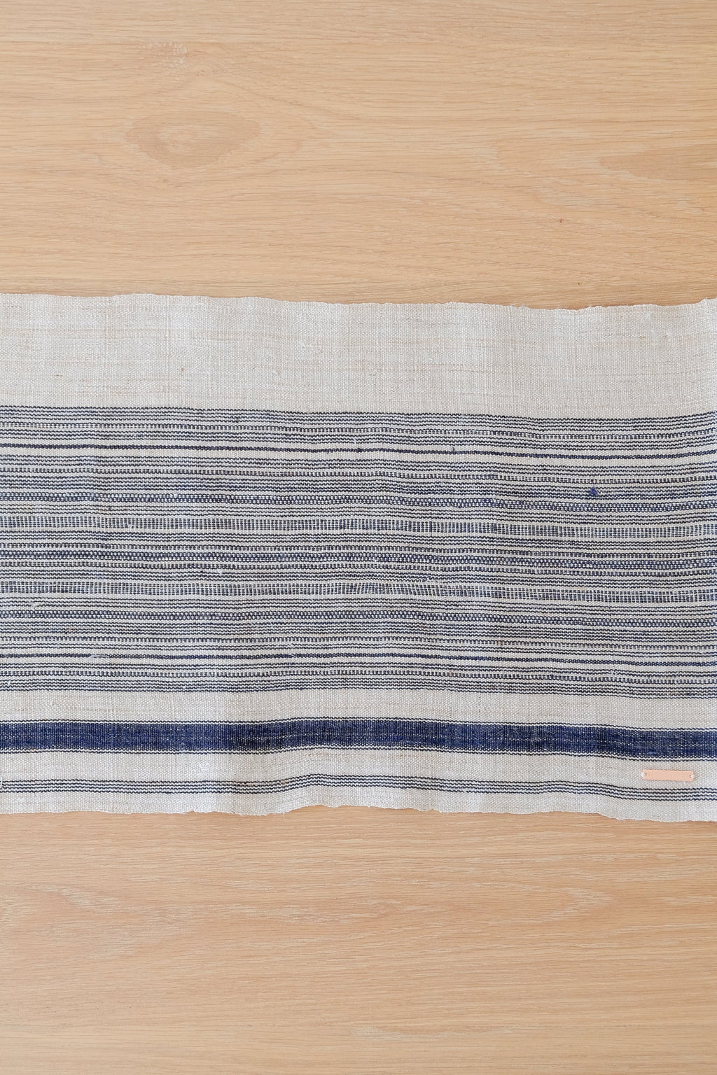 Vintage striped table runner with indigo and cream hemp fabric on wooden surface