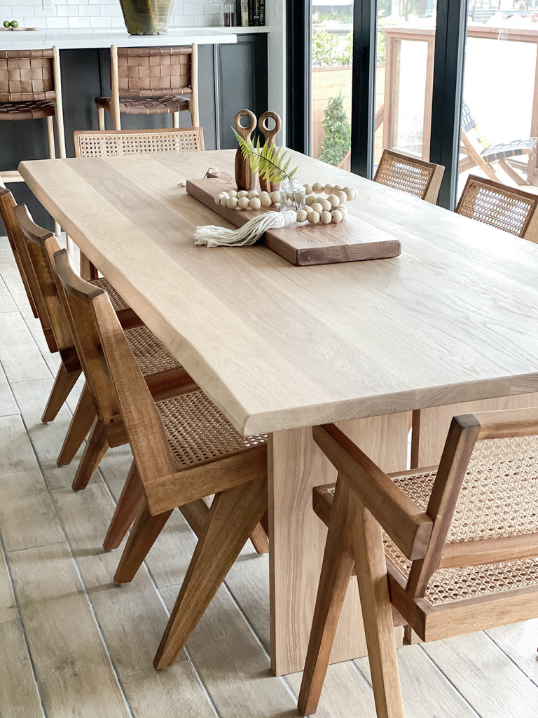 Close up angled view of White Oak Live Edge Table with Woven Leather Strap Bar Stools and Woven Leather Strap Backless Counter Stools - Saddle in a beautiful kitchen. - Saffron and Poe