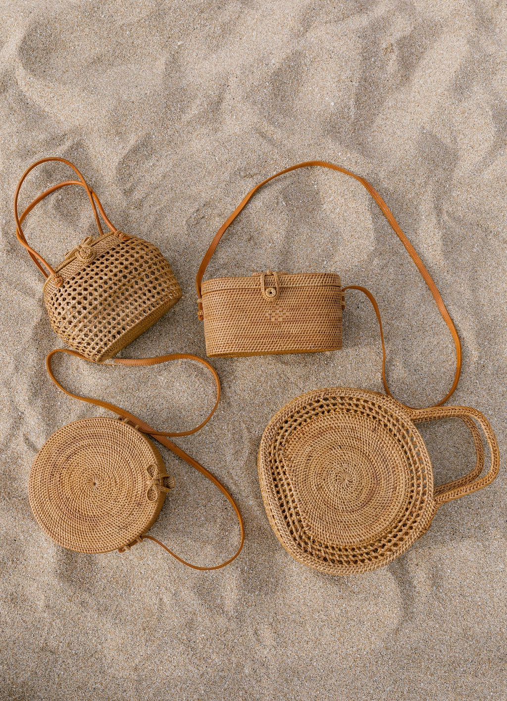 Collection of handcrafted Tenganan Basket Handbags displayed on sand