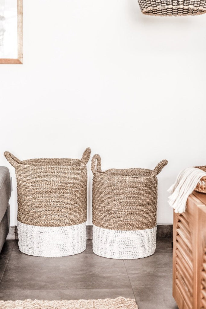 Two cream-colored with white base Structured Hyacinth storage baskets with handles against white wall. Handmade in Bali using natural water hyacinth  - Saffron and Poe