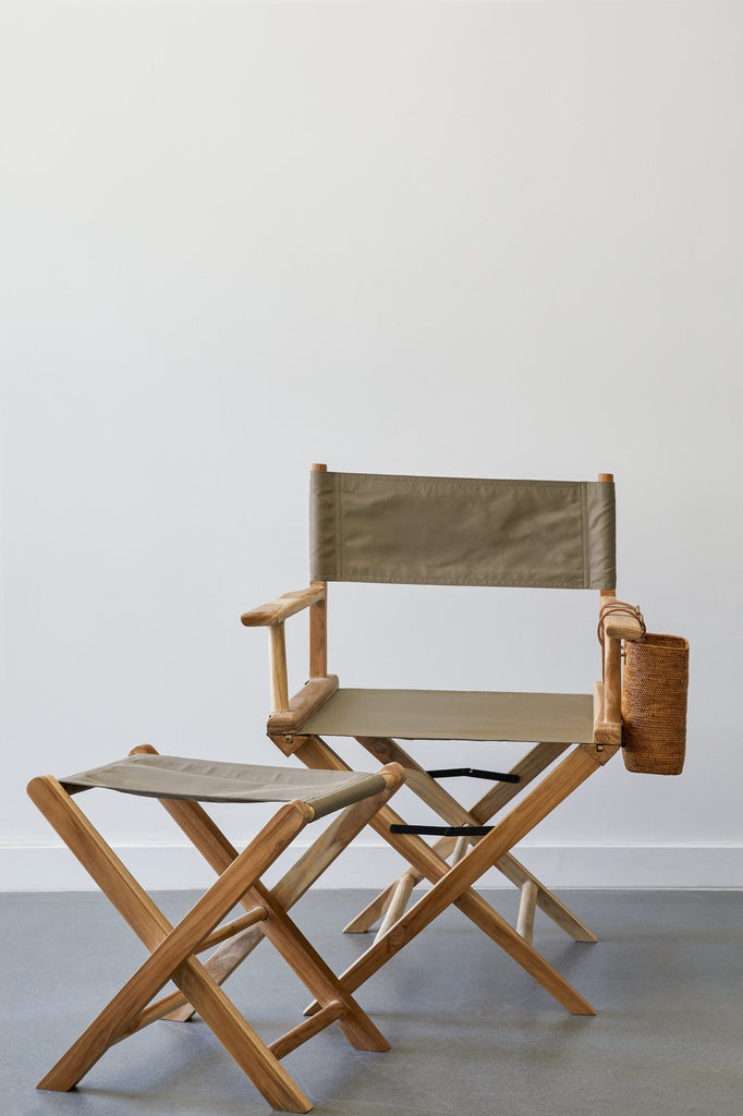 Front view of Taupe Canvas Director's Chair with Taupe Canvas Folding Stool and Tenganan Side Basket against a white background with concrete flooring. - Saffron and Poe