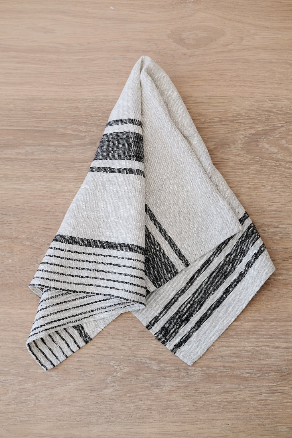 Set of two dark grey stripe linen hand towels on wooden surface